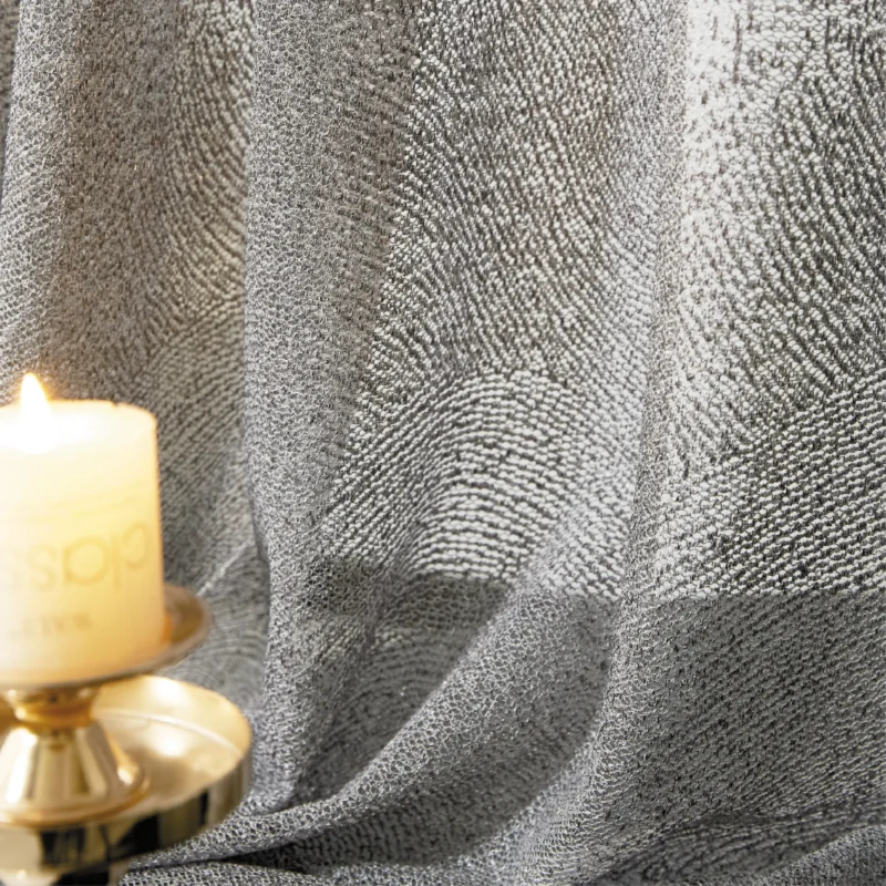 Ripple textured sheer curtain illuminated by warm candlelight, showing soft wave patterns.