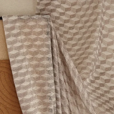 Close-up of beige jacquard sheer curtain with soft folds and geometric texture