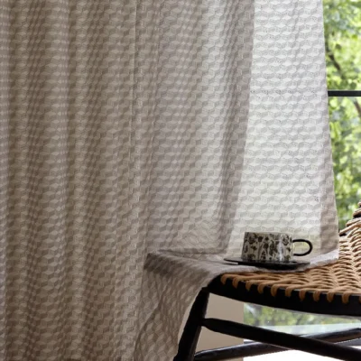 Light brown jacquard sheer curtain with geometric pattern beside a modern window desk