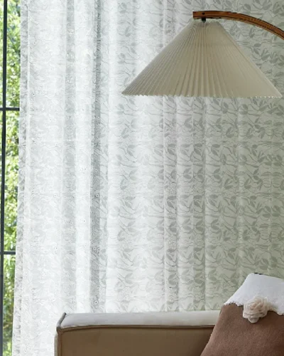Dual-tone jacquard sheer curtain with leaf pattern softly diffusing daylight in a cozy bedroom corner.