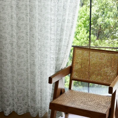 Willow Whisper Curtain hanging beside a rattan chair with natural light.
