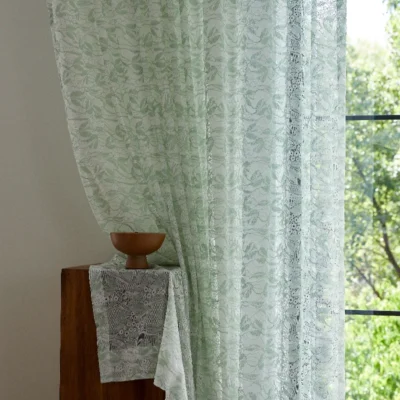 Close-up of Willow Whisper Curtain with sunlight and greenery outside.