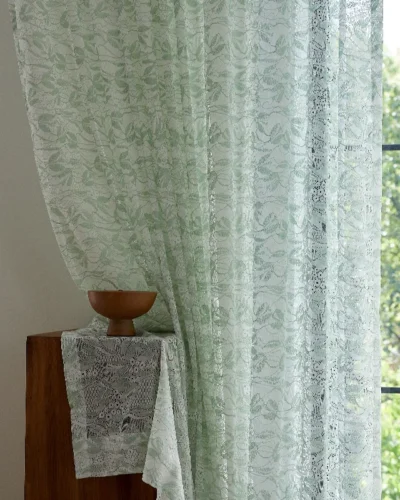 Close-up of Willow Whisper Curtain with sunlight and greenery outside.