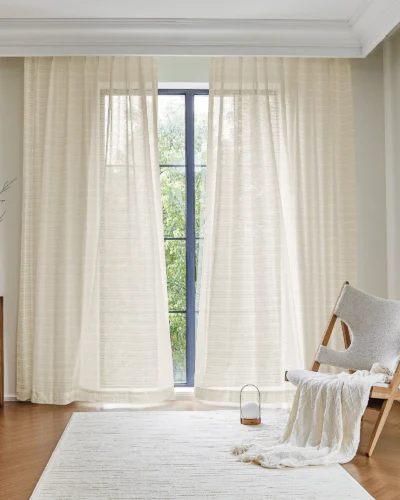 Soft white jacquard sheer curtain with scale-like pattern hanging in a minimal living space