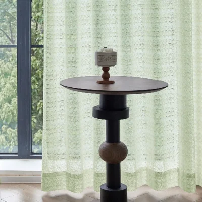 Light green jacquard sheer curtain with geometric botanical patterns by the window