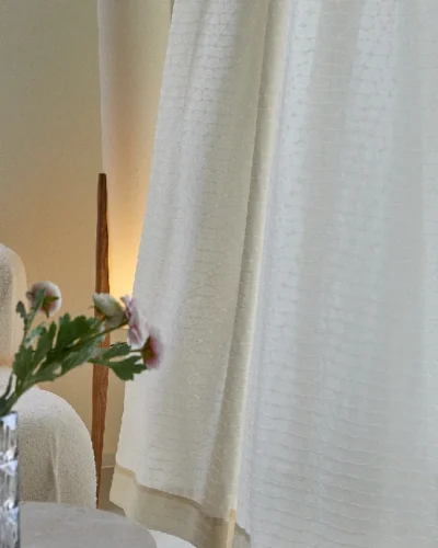 Echo Leaf curtain in soft jacquard voile draping beside a flower vase