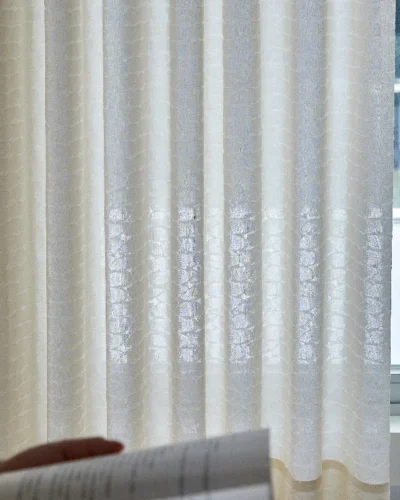 Echo Leaf layered jacquard curtain held by hand, showing texture and light filtering effect