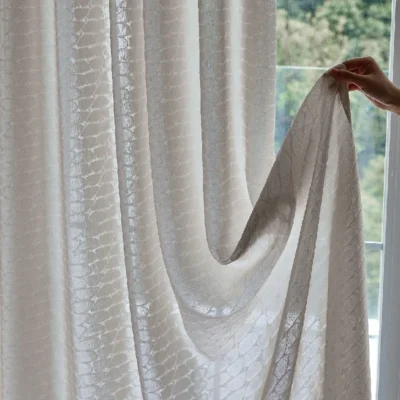 Hand holding Echo Leaf curtain edge to show jacquard texture and light-filtering fabric
