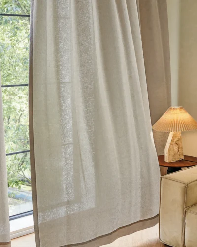 Sheer jacquard curtain flowing softly near window with warm indoor lighting