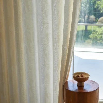 Elegant sheer curtain with botanical jacquard pattern, softly filtering sunlight in a bright interior