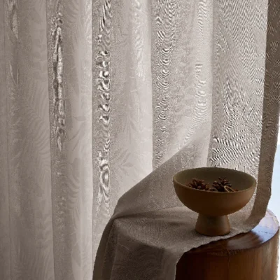 Sheer jacquard curtain with soft botanical texture beside wooden decor