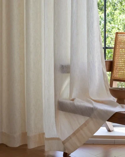 Botanical jacquard sheer curtain gently draped by a window with a woven chair nearby