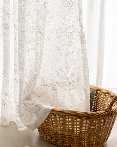 Rope-embroidered floral sheer curtain panel in ivory, light-filtering lace with airy drape beside a window.