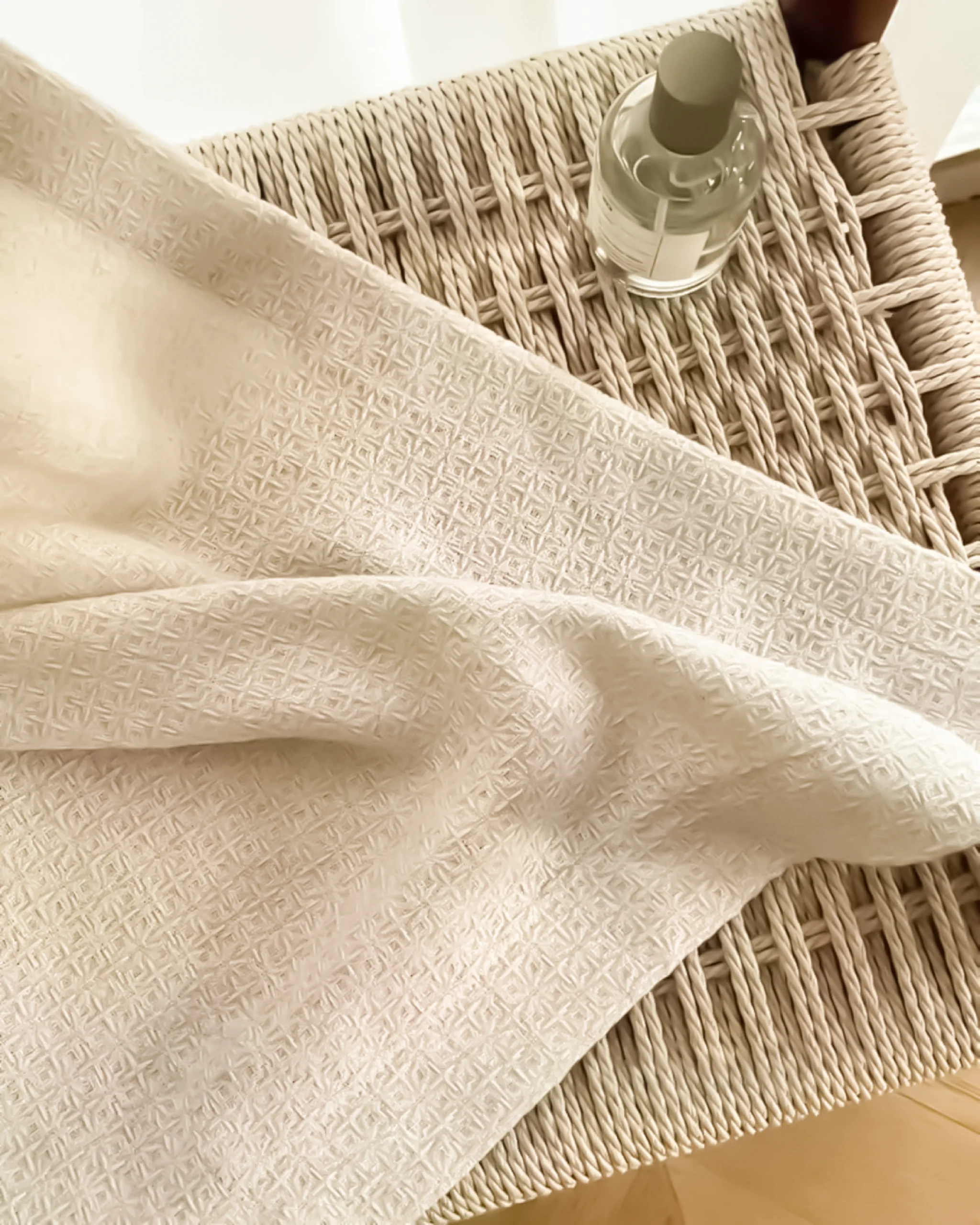 Soft textured curtain fabric with a refined lattice weave, draped over a woven tray – textured curtain fabric detail for custom curtains.