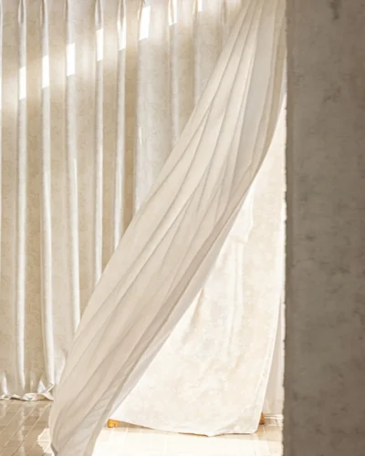 Soft beige floral jacquard shade curtain draped by a window, textured fabric with gentle light.