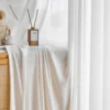 Fine Ridge Texture Curtain in soft matte ivory draped beside a wooden cabinet with a reed diffuser, hanging in a bright room.