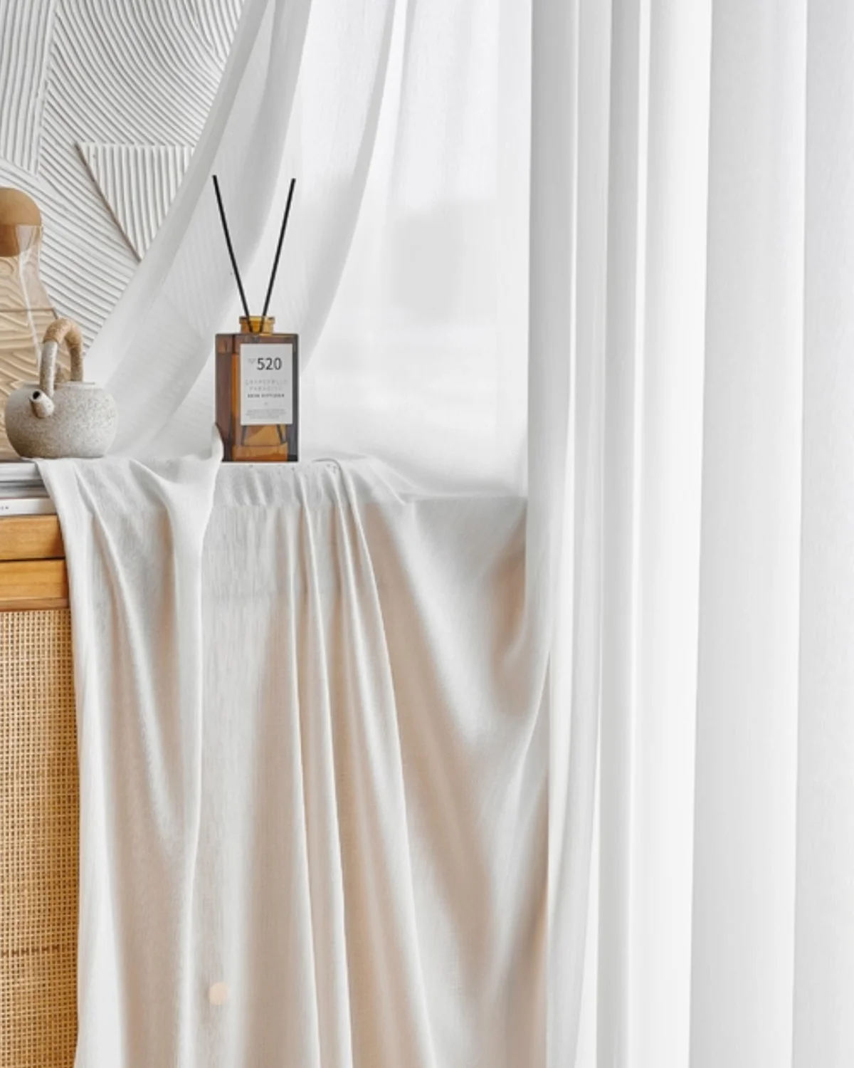 Fine Ridge Texture Curtain in soft matte ivory draped beside a wooden cabinet with a reed diffuser, hanging in a bright room.