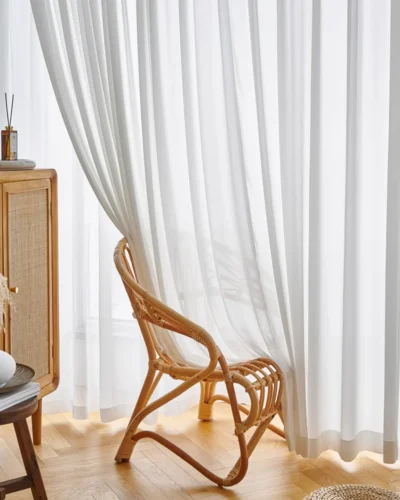 Fine Ridge Texture Curtain in soft matte ivory hanging behind a rattan chair in a bright living room.