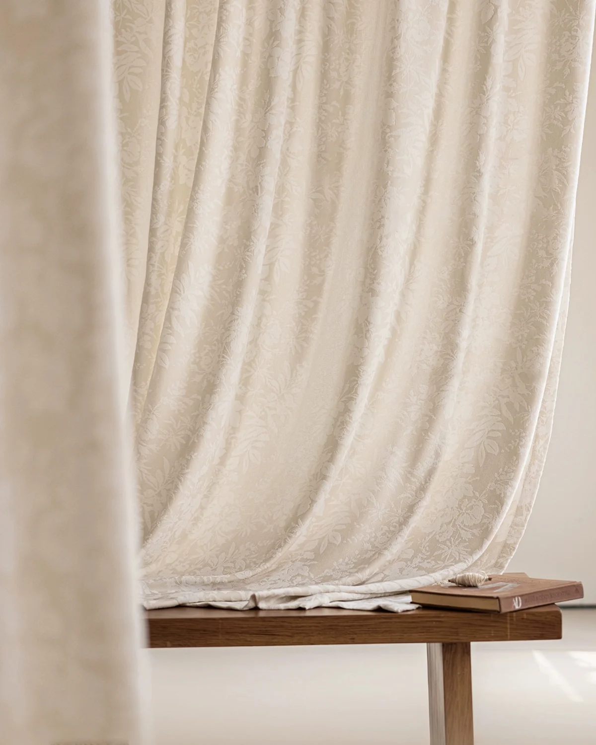 Blossom Whisper sheer curtain in beige floral jacquard, softly draped behind a simple wooden bench