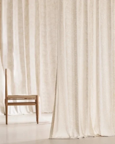 Blossom Whisper sheer curtain in beige floral jacquard hanging to the floor beside a simple wooden bench