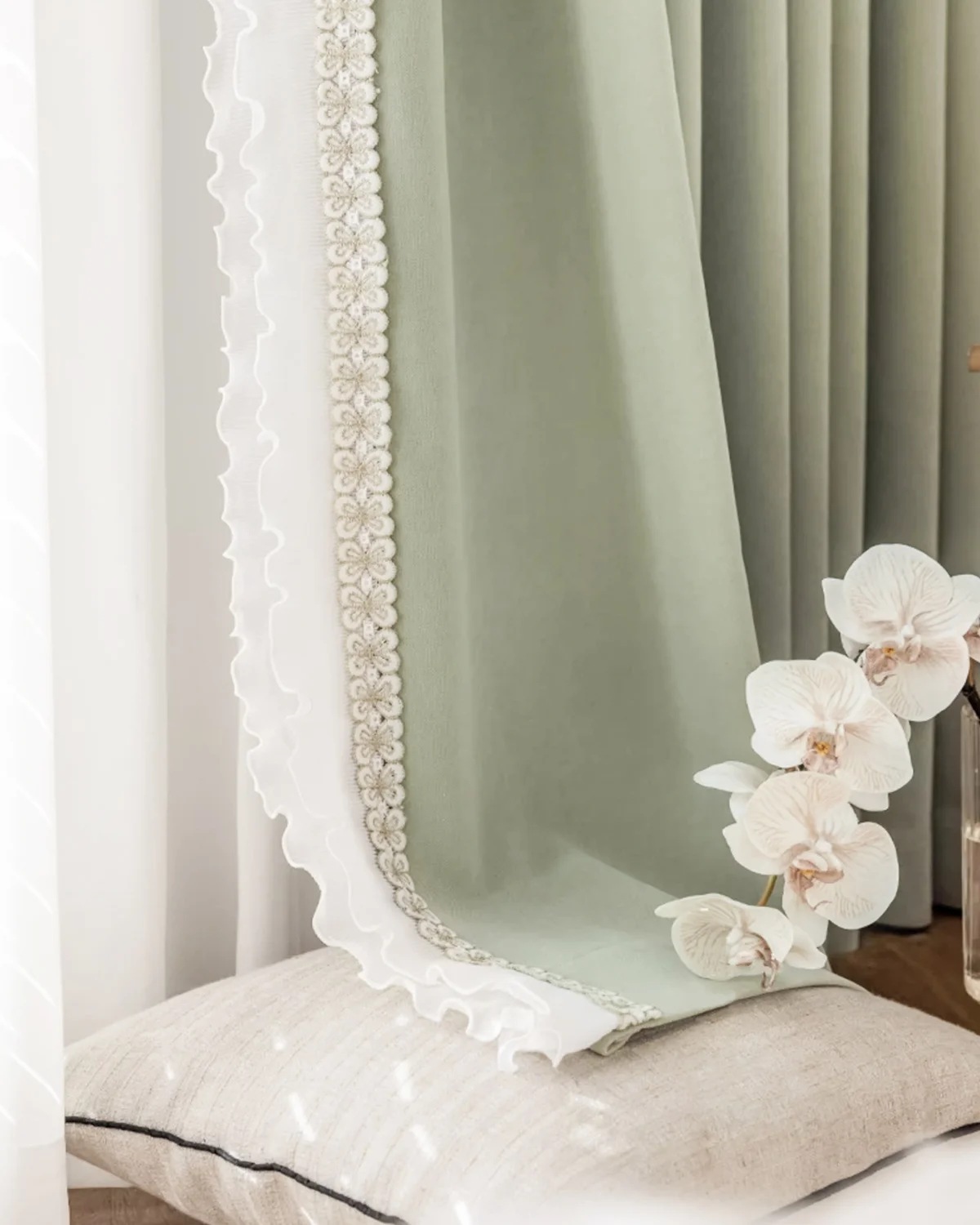 Sage green lace curtain panels in a bright bedroom, floor-length with soft pleats