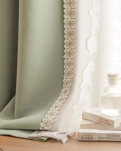 Sage green curtain edge with floral lace trim layered over white sheer, styled with books and a vase