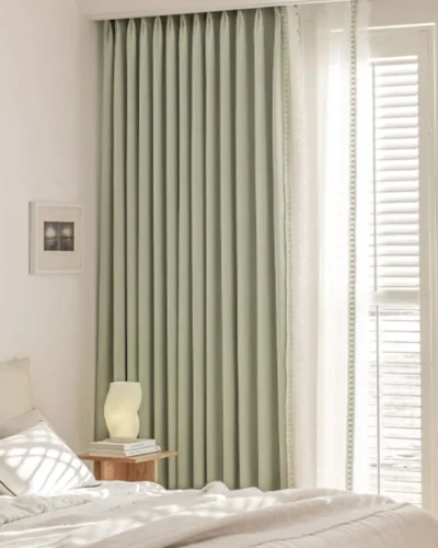Sage green lace curtain panels in a bright bedroom, floor-length with soft pleats