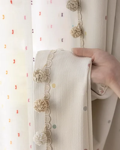 Macaron dot pom pom curtain fabric swatch – soft cream textured weave with pastel coloured dots.