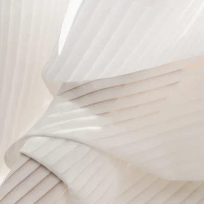 Close-up of vertical stripe sheer curtain in soft textured white voile, folded to show the woven details.