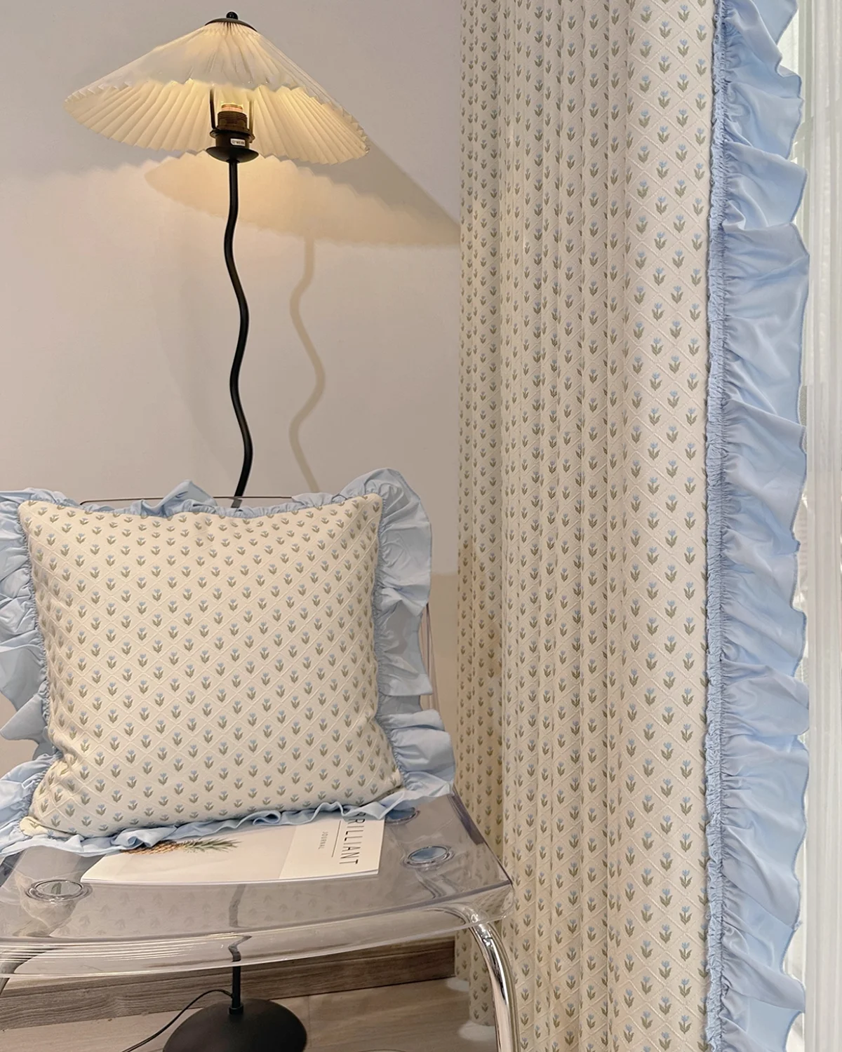 Embroidered sheer curtain with petite floral pattern styled in a cosy bedroom corner