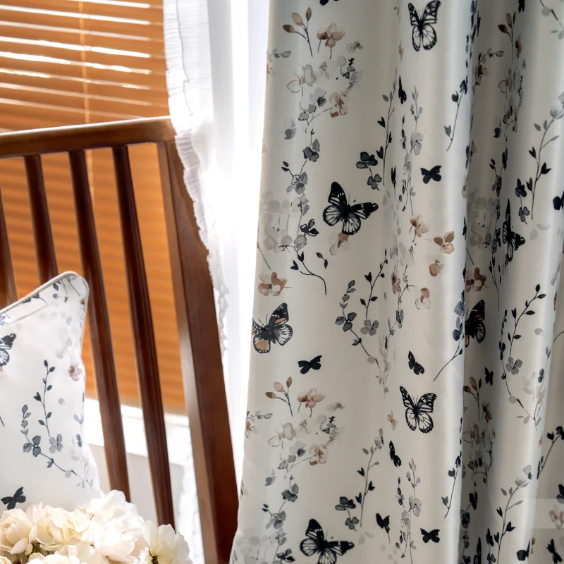 Close-up of butterfly print curtain with floral details, softly lit by natural daylight.
