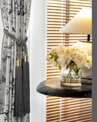 Close-up of ink bamboo curtain with pleats, styled with flowers and wood decor