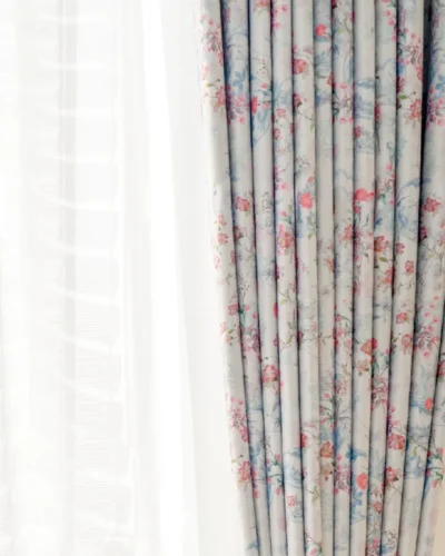 Bird and floral curtain with gentle pleats and light filtering beside window