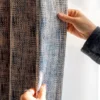 Hand touching Woven Print Curtain in indigo and beige, showing faux woven texture and soft drape