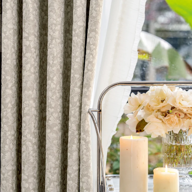 Floral Realm Curtain in soft beige, styled beside flowers and candles in a serene setting