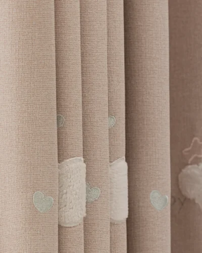 Close-up of cloud embroidery on pink kids curtain with soft textured fabric.