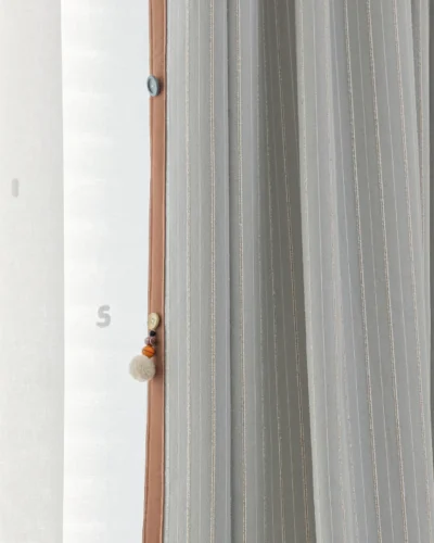 Side view of Whisper Stripe Curtain in mist grey with soft vertical lines and subtle children's room details