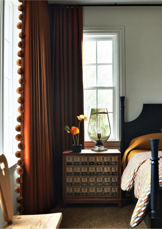 Eden Pom Tassel Trim on brown curtain in cozy bedroom setting