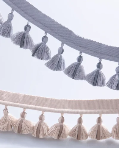 Side-by-side view of single-layer tassel fringe trims in gray blue and beige tones, showing color options