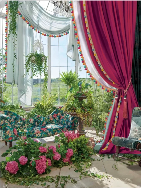 Wine red curtain with tieback styled beside a floral conservatory window – romantic garden view