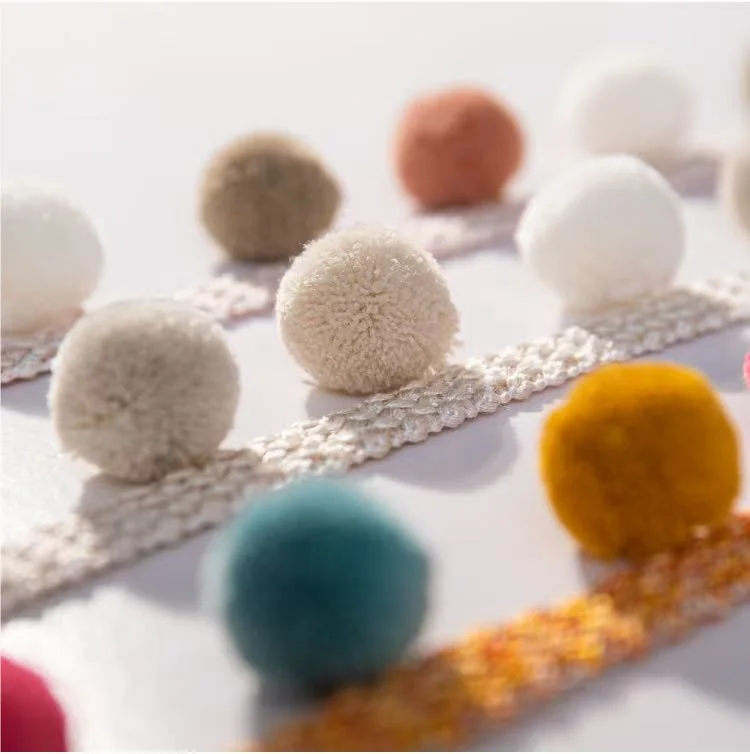 Assorted Eden pom pom trim colors in close-up view – ivory, taupe, teal, gold, and more