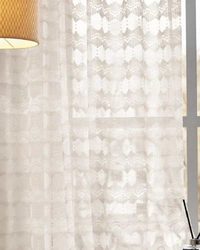 Lace curtain with geometric weave softly filtering light in a cozy room