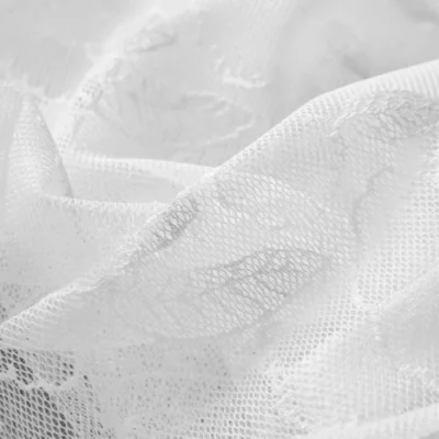 Close-up of white sheer curtain with delicate leaf embroidery texture