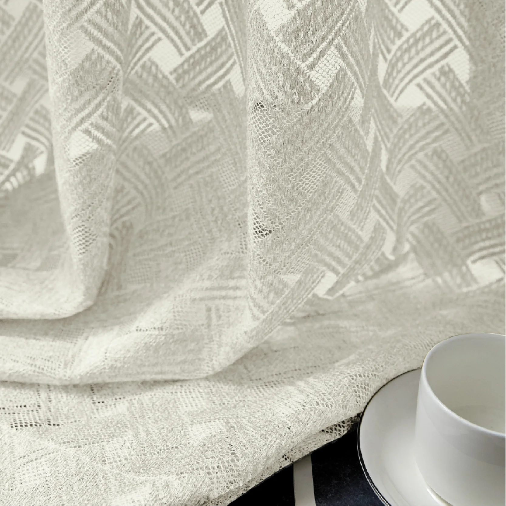 Close-up of Serene Weave Sheer Curtain fabric with soft jacquard texture and tableware
