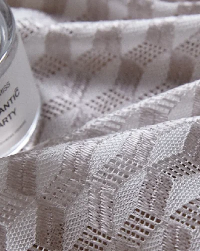 Close-up of geometric jacquard curtain fabric with fragrance bottle