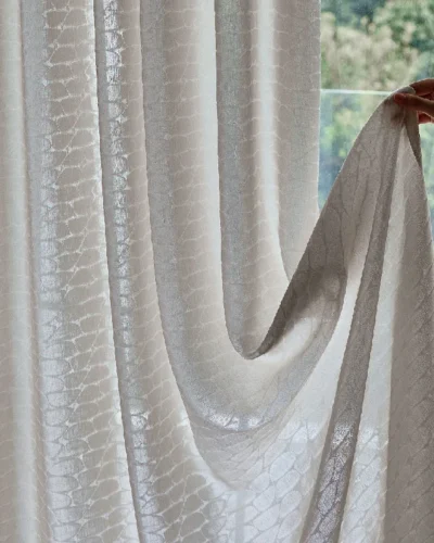 Hand holding Echo Leaf curtain edge to show jacquard texture and light-filtering fabric