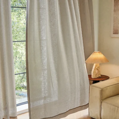 Sheer jacquard curtain flowing softly near window with warm indoor lighting