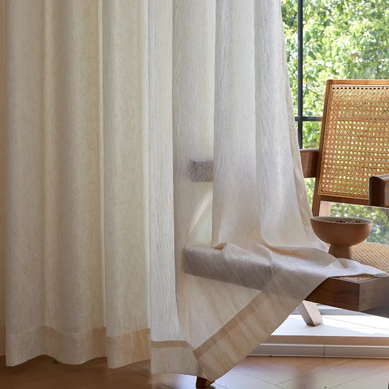 Botanical jacquard sheer curtain gently draped by a window with a woven chair nearby