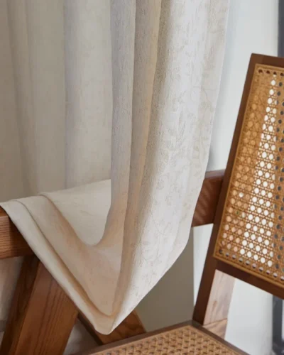 Botanical jacquard sheer curtain resting over a woven rattan chair