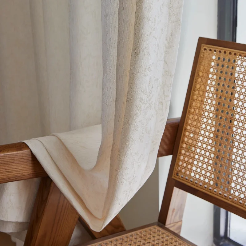 Botanical jacquard sheer curtain resting over a woven rattan chair
